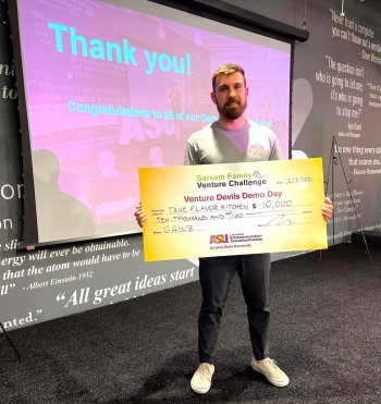 Tyler Perez holds oversized check showing his $10,000 win from Venture Devils Demo Day.