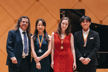 Bösendorfer and Yamaha USASU International Piano Competition winners standing in a line next to one another, smiling for the camera and wearing their medals.