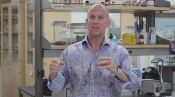 ASU Professor Jeff Yarger speaking and gesturing with his hands in a laboratory setting.