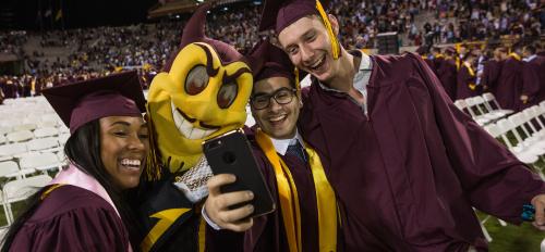 New ASU graduates pose with Sparky at commencement