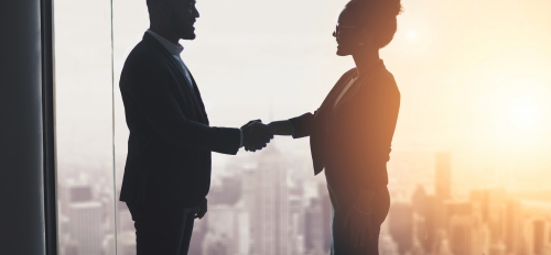 Two people shaking hands in an office.
