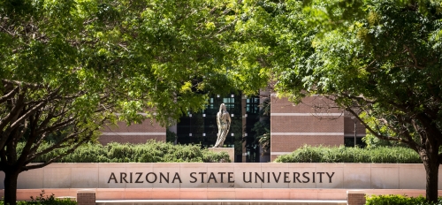 A statue stands above an ASU sign framed by green trees