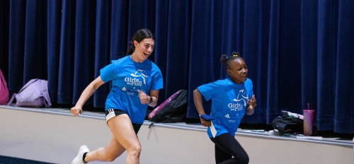 ASU student and elementary school student running in gym