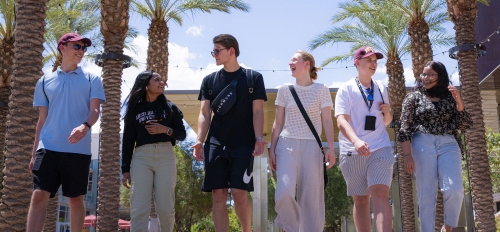 A line of students smiling as they walk on campus