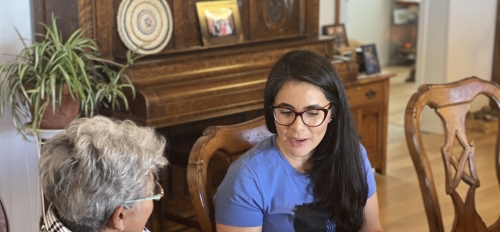 Older woman Angela Murphy seated at a dining table in her home in Concho, AZ, as she speaks with ASU Associate Professor Vanessa Fonseca-Chávez.