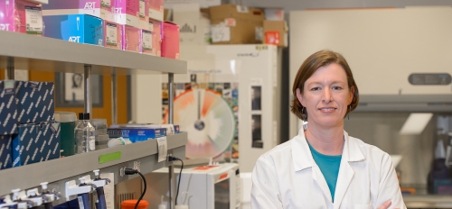ASU Regents Professor Anne Stone in a white coat in a lab.