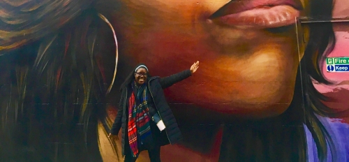 Woman standing in front of a mural of Michelle Obama.