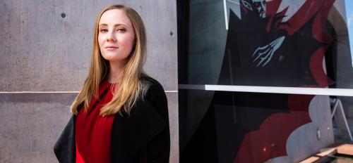 woman standing next to a painting of dracula