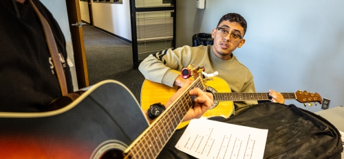 Veteran playing a guitar at a desk.