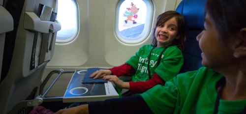 Children smile on an airplane.