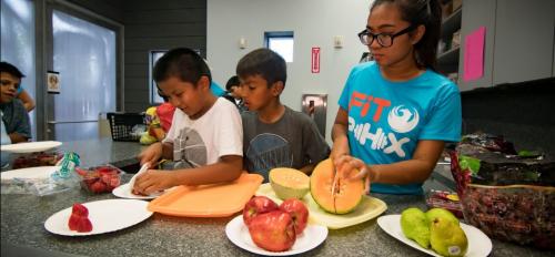 young kids cutting fruit