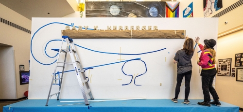 Two students drawing a mural.