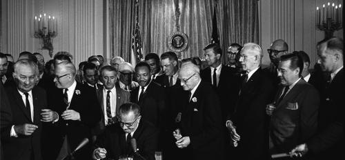 black and white photo of a group of male politicians signing the civil rights act of 1964