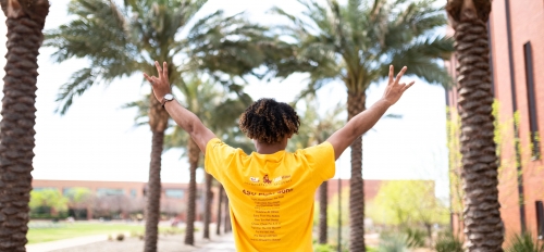 A student giving forks up on palm walk  on ASU's Tempe campus