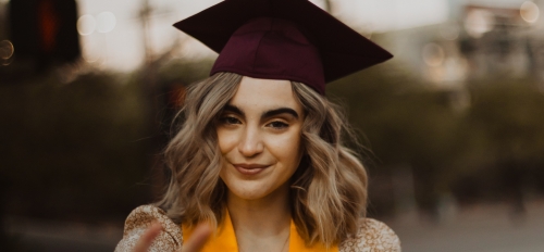 Woman in a cap and gown with a stole giving the forks up sign, Cheyenne Kratz portrait