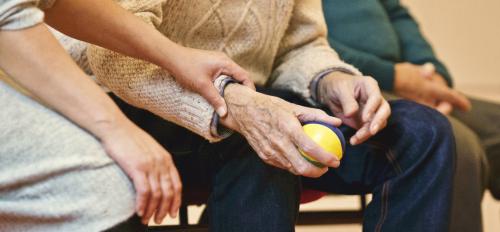 old man holding a ball while a nurse touches his wrist