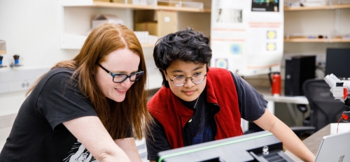 two students in a lab look at computer equipment
