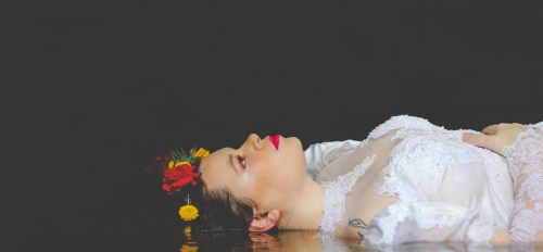 Portrait of Ophelia, lying in the water, with a black background.