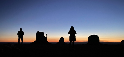 Two people silhouetted against a backdrop of desert scenery.