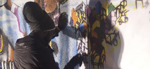 Graffiti artist works on mural
