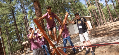 An ASU student prepares to walk across a slack rope as fellow students look on.