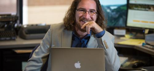 ASU professor Greg Wise sits at a laptop in his office