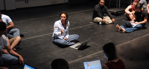 ASU Associate Professor Grisha Coleman sitting on the floor teaching a group of students