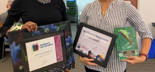 Two women stand side-by-side holding their framed awards.