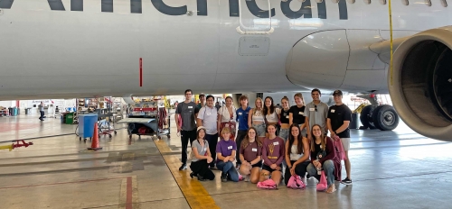 Group of ASU students pose in front of American Airlines plane.