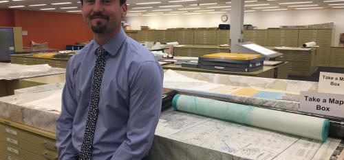 director of Map and Geospatial Hub standing in front of old maps