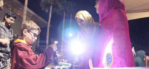 Above: Hira Rehman (in pink) and Asma Shamim (in gold) demonstrate the power of photovoltaics with members of the Tempe community during Night of the Open Door. Photographer Erika Gronek/ASU