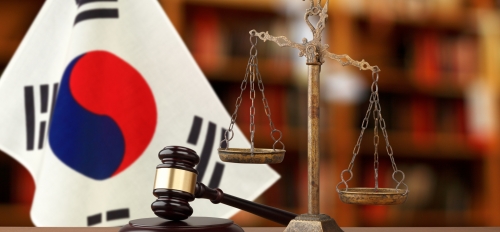 Gavel and justice scales in front of Korean flag.