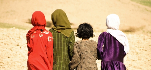 Four Afghanistan girls walking in the mountains, facing away from the camera.