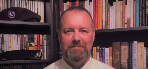 Headshot of ASU Online student John Rose in front of a bookcase.