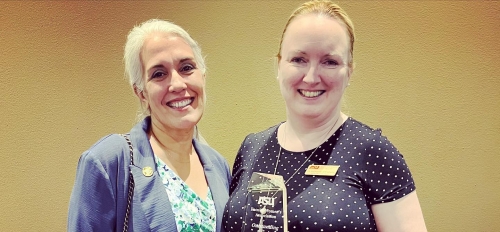 Katherine O'Flaherty, Honors Faculty Fellow in Barrett, The Honors College at ASU, standing next to another woman while smiling and holding an award.