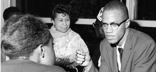 Photo of Malcom X having a discussion with two women.