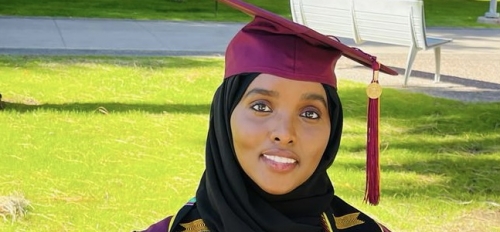 ASU student Maryam Abdulle poses for a photo in a graduation gown and cap, holding her diploma cover