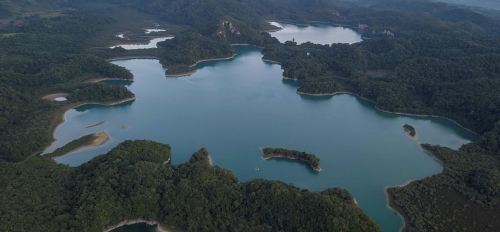 Aerial view of a landscape with a large lake and vegetation and smaller bodies of water around it.