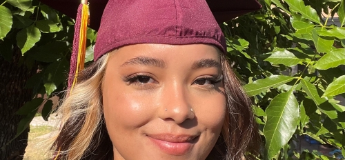 Headshot selfie of Sierra Lockett in graduation cap, in an outdoor setting.