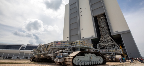 A NASA transporter sits outside a large building.