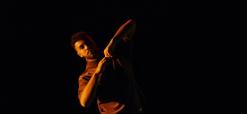 A dancer performs on a dark stage