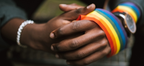 Rainbow ribbon wrapped around a Black person's hands.