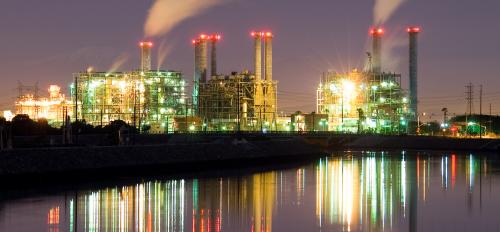 Lights of a power plant are reflected in a lake at night.