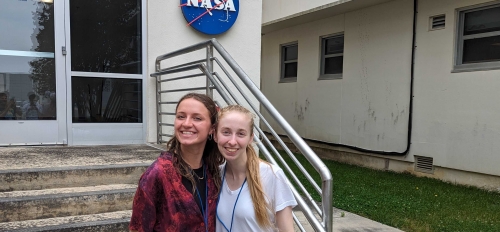 ASU students Sadie Cullings and Noelle Geddis pose in front of a building with a NASA logo on it.