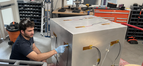 ASU student worker Matthew Adkins working on a cubesat in a lab.