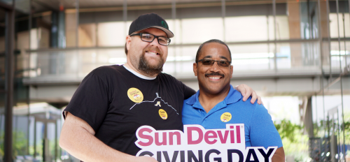 Two men hold a sign that reads "Sun Devil Giving Day."