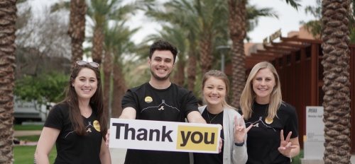Four people hold a thank you sign to show support of Sun Devil Giving Day.