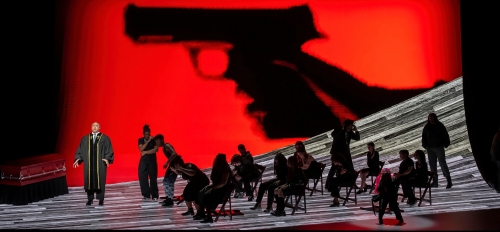 Scene from The Walkers with a group of people gathered in front of a red backdrop with a gun.