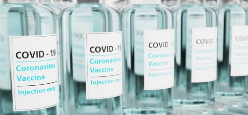 Bottles on a table labeled "Covid-19 Coronavirus Vaccine."