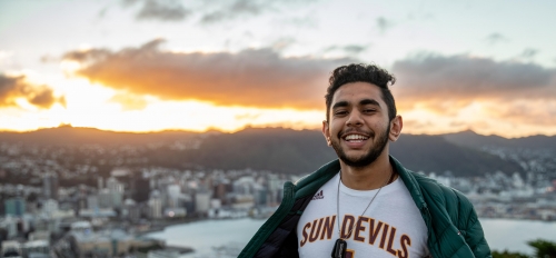 man wearing ASU Sun Devils jersey on a mountain with a city in the background